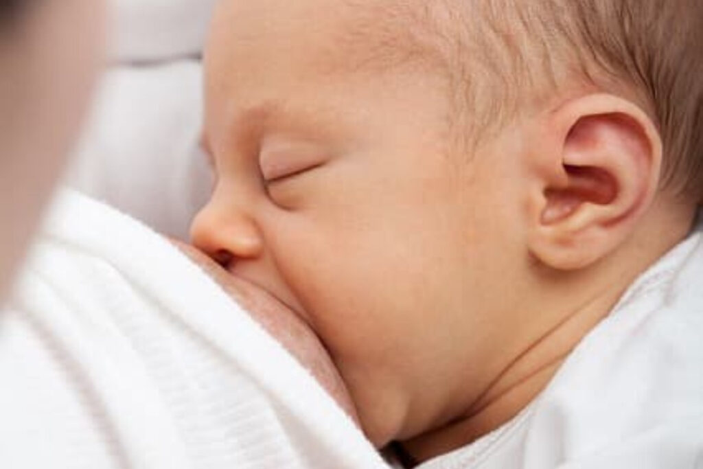 Imagem de bebê recém-nascido mamando no seio.